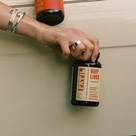Hand holding a bottle of FRTIL grass-fed and finished beef liver supplement in a lifestyle setting.